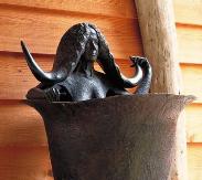 close up photo of a bronze sculpture of a women with large horns sitting in a deep tub.